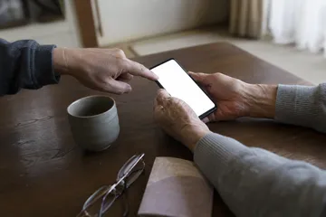 居間で、ご家族にスマートフォンの操作を教わる